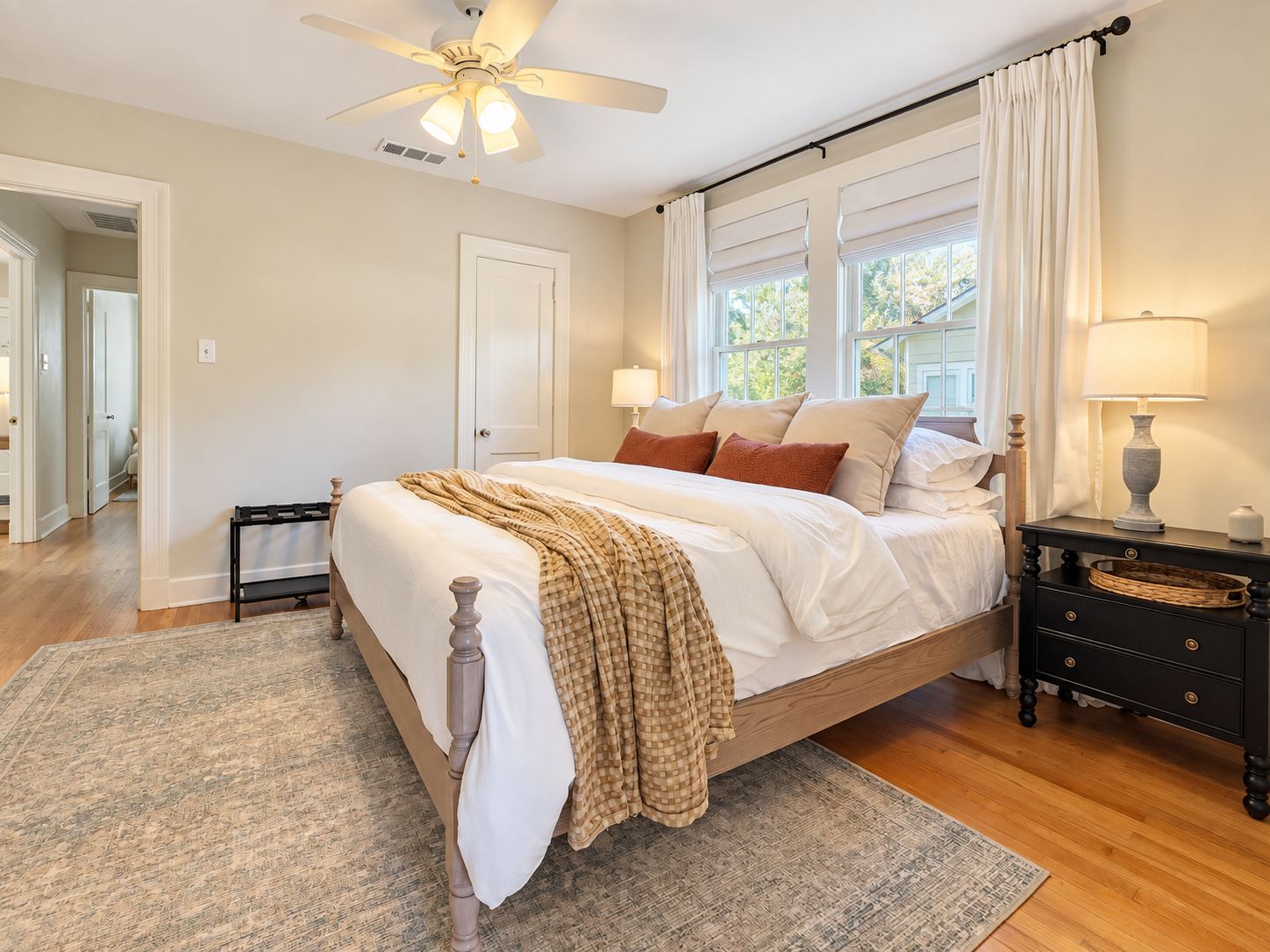 A bedroom with a bed, bedside tables, a ceiling fan, and a window with curtains.