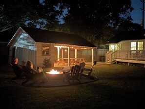 Een achtertuin met een houten terras, een overdekte patio en een vuurkorf.