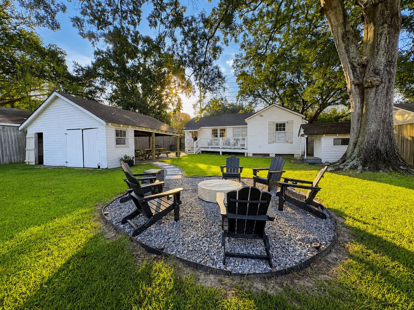 A backyard with a circular seating area, a barbecue grill, and a covered picnic table.
