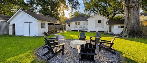 A backyard with a circular seating area, a barbecue grill, and a covered picnic table.