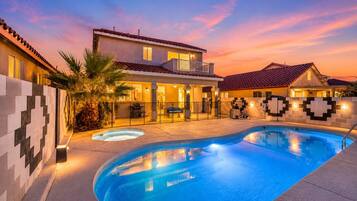 A residential property with a swimming pool, a two-story house with a balcony, and a patio area.