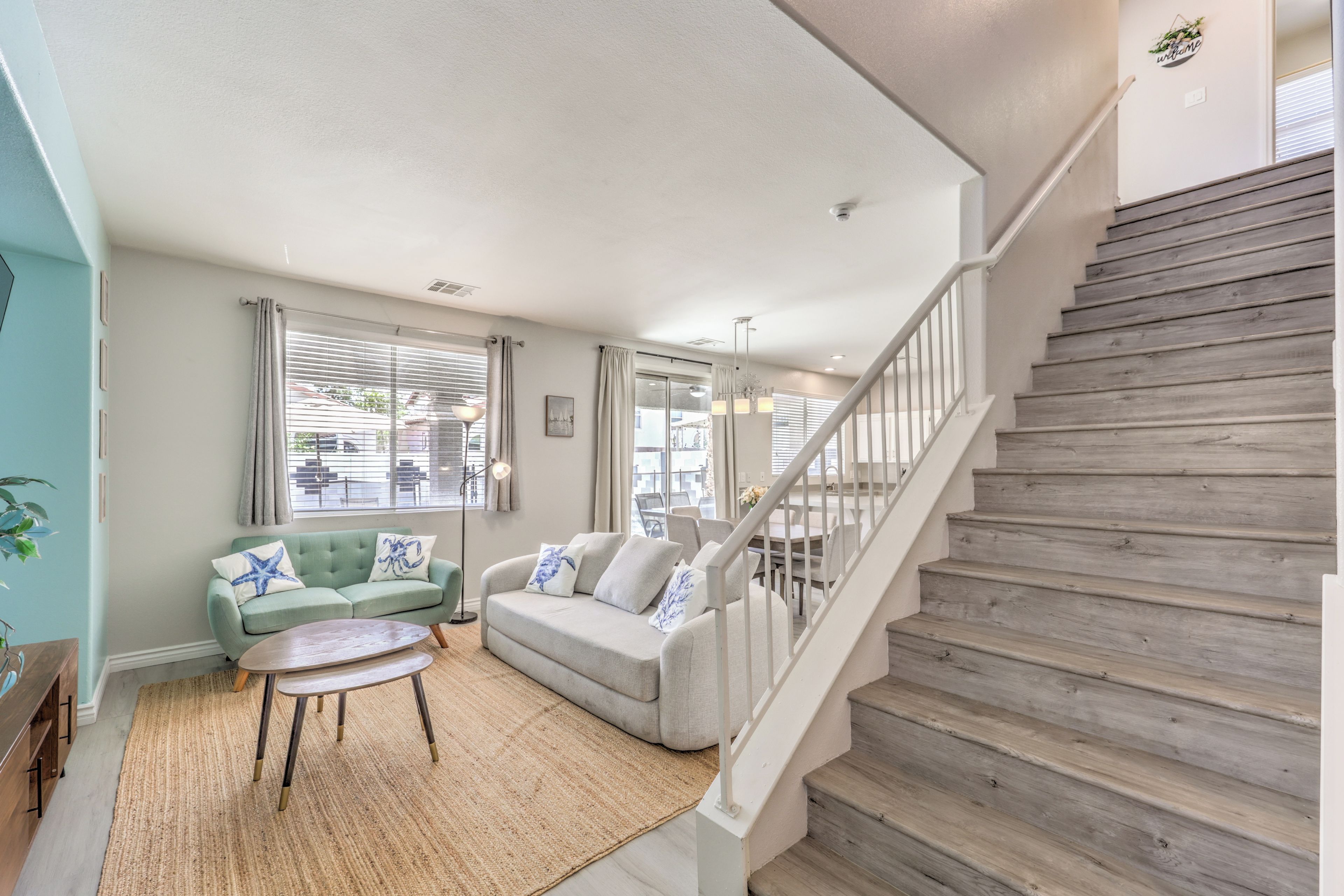 Un salon avec un escalier, un canapé, une table basse et une vue sur l’extérieur.