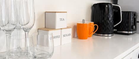 A kitchen counter with a framed artwork, coffee and tea boxes, and a coffee maker.