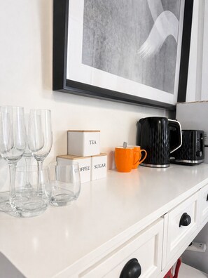 A kitchen counter with a framed artwork, coffee and tea boxes, and a coffee maker.