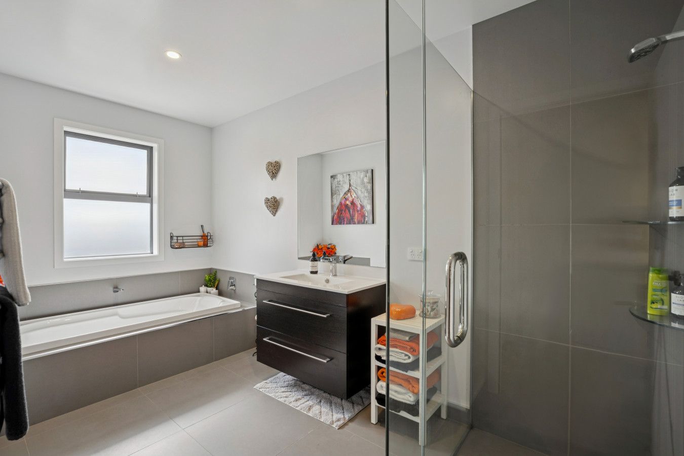 A modern bathroom with a bathtub, vanity, and shower.