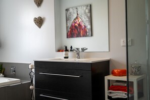 Un baño con lavamanos blanco, mueble negro y espejo encima.
