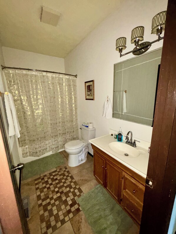 A bathroom with a toilet, sink, mirror, and shower curtain.
