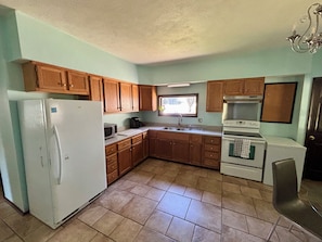 A kitchen with wooden cabinets, a refrigerator, a stove, and a sink.