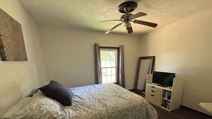 Una camera da letto con un letto, una cassettiera, una televisione e una ventola a soffitto.