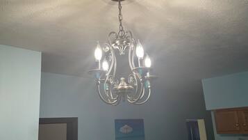 Een kroonluchter met meerdere lampen hangt aan het plafond in een kamer met lichtblauwe wanden.