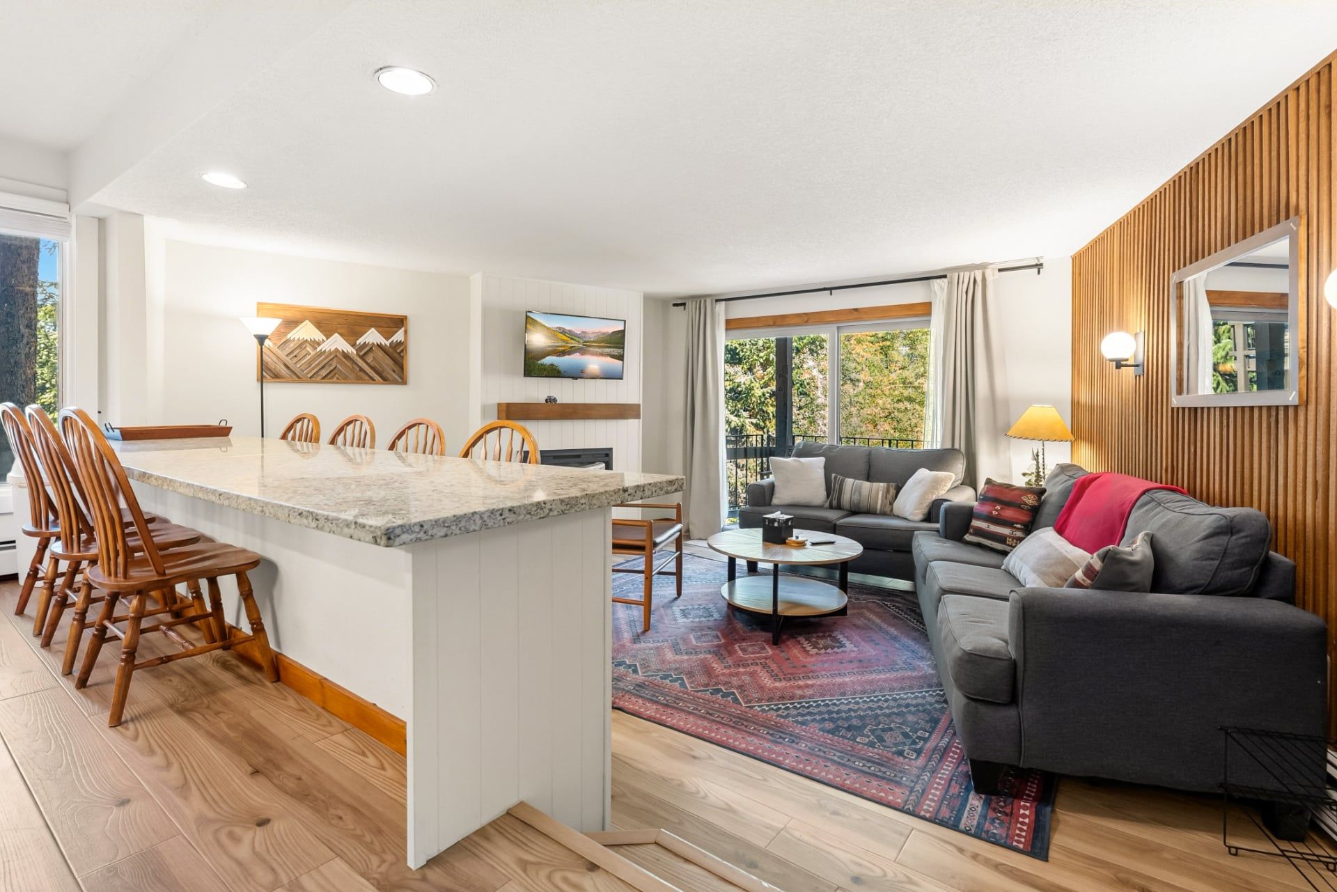 A modern living space with a kitchen island, dining area, and a cozy seating area with a sofa and rug.