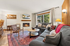 A living room with a fireplace, a sofa, a coffee table, and a TV mounted on the wall. - 5 Beds, Sleeps 8, Walkable to Peak 8 Lifts, Free Bus Outside (Breckenridge)