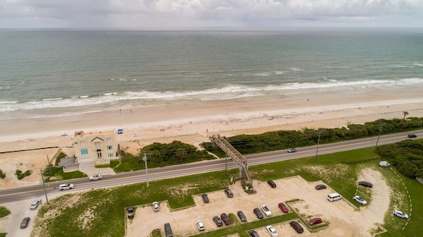 Une route côtière bordée d’une plage et d’un bâtiment surmonté d’un toit bleu.