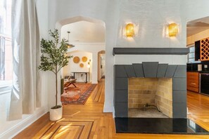 A modern interior with a fireplace, wooden flooring, and a dining area with a table and chairs. - 5 Bedroom | Home Near Wynwood | Pool |Free Parking (Miami)