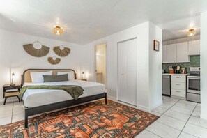 A bedroom with a bed, bedside tables, a rug, and a wall-mounted light fixture. - 5 Bedroom | Home Near Wynwood | Pool |Free Parking (Miami)