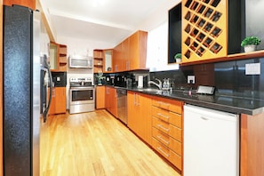 A modern kitchen with wooden cabinets, stainless steel appliances, and a black countertop.
