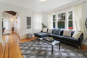 A modern living room with a sectional sofa, a glass coffee table, and a patterned rug.