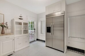 A kitchen with white cabinetry, a stainless steel refrigerator, and a patterned floor.