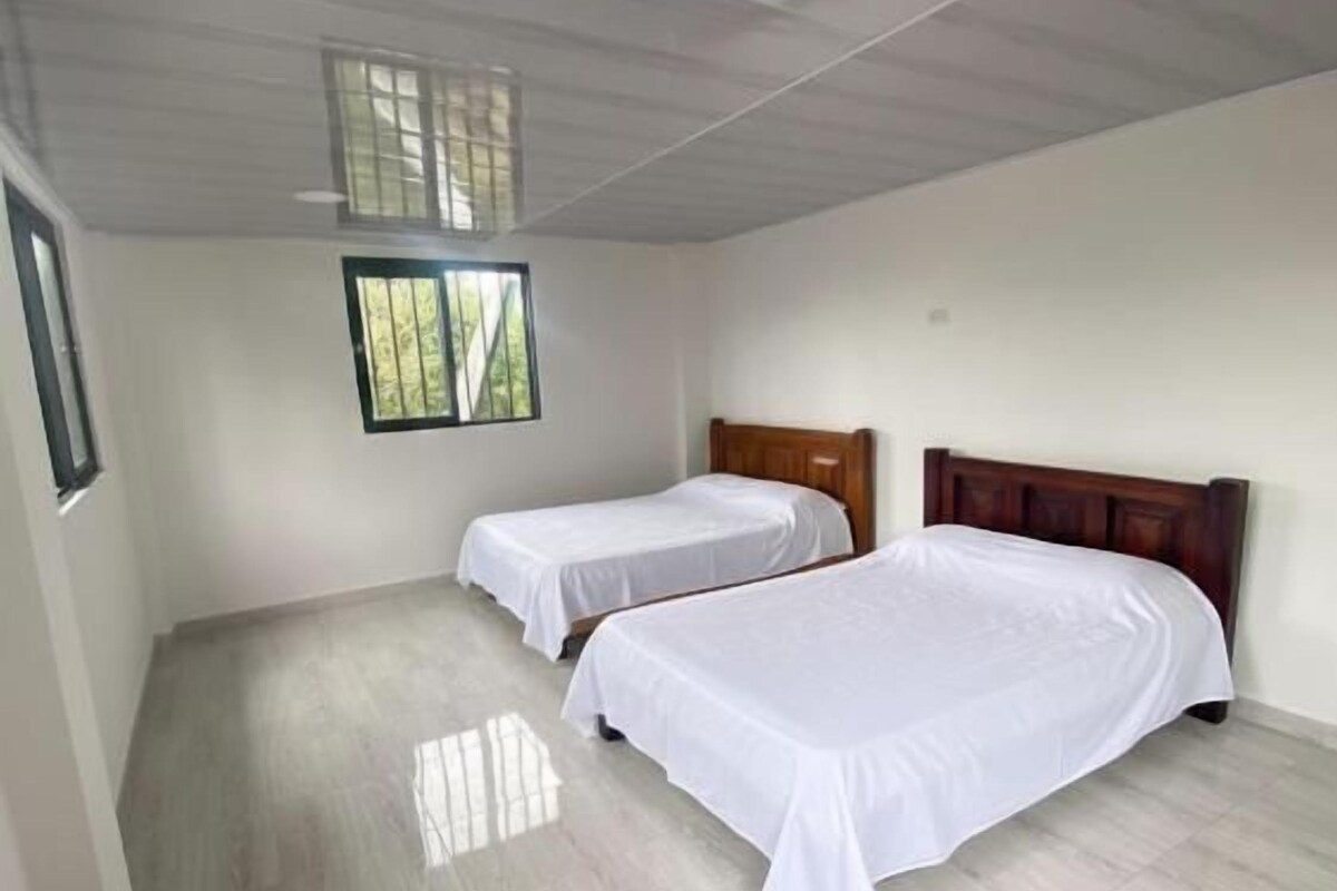 Quarto com duas camas, janela e teto de madeira.