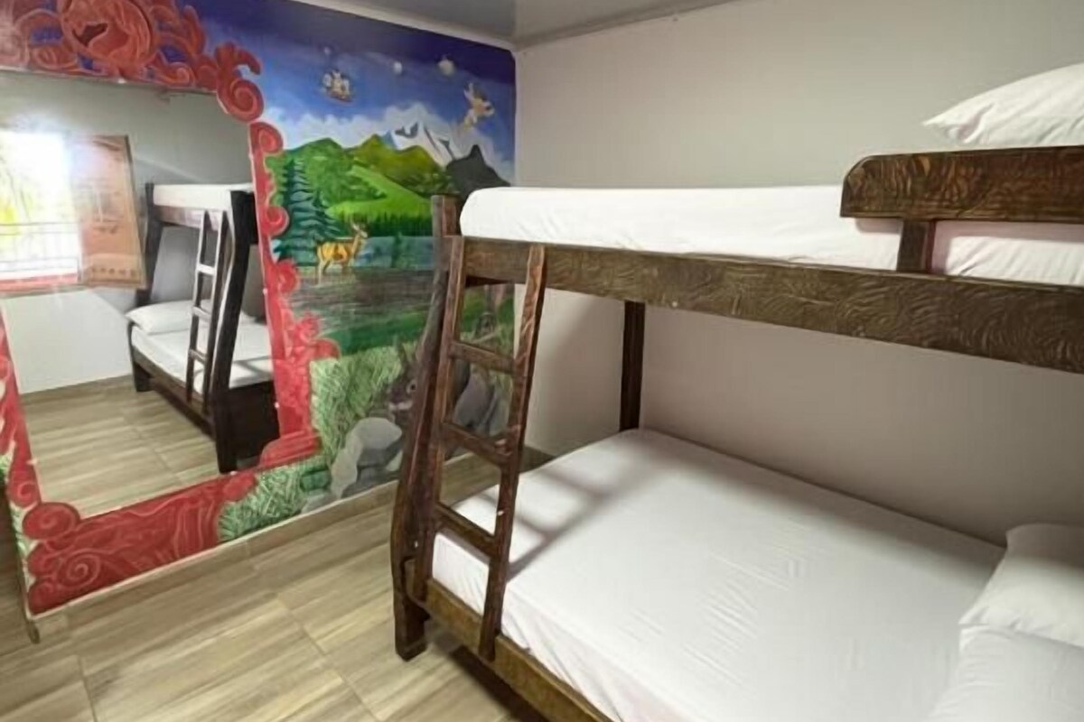 Quarto com beliche, um mural na parede e uma escrivaninha com cadeira.