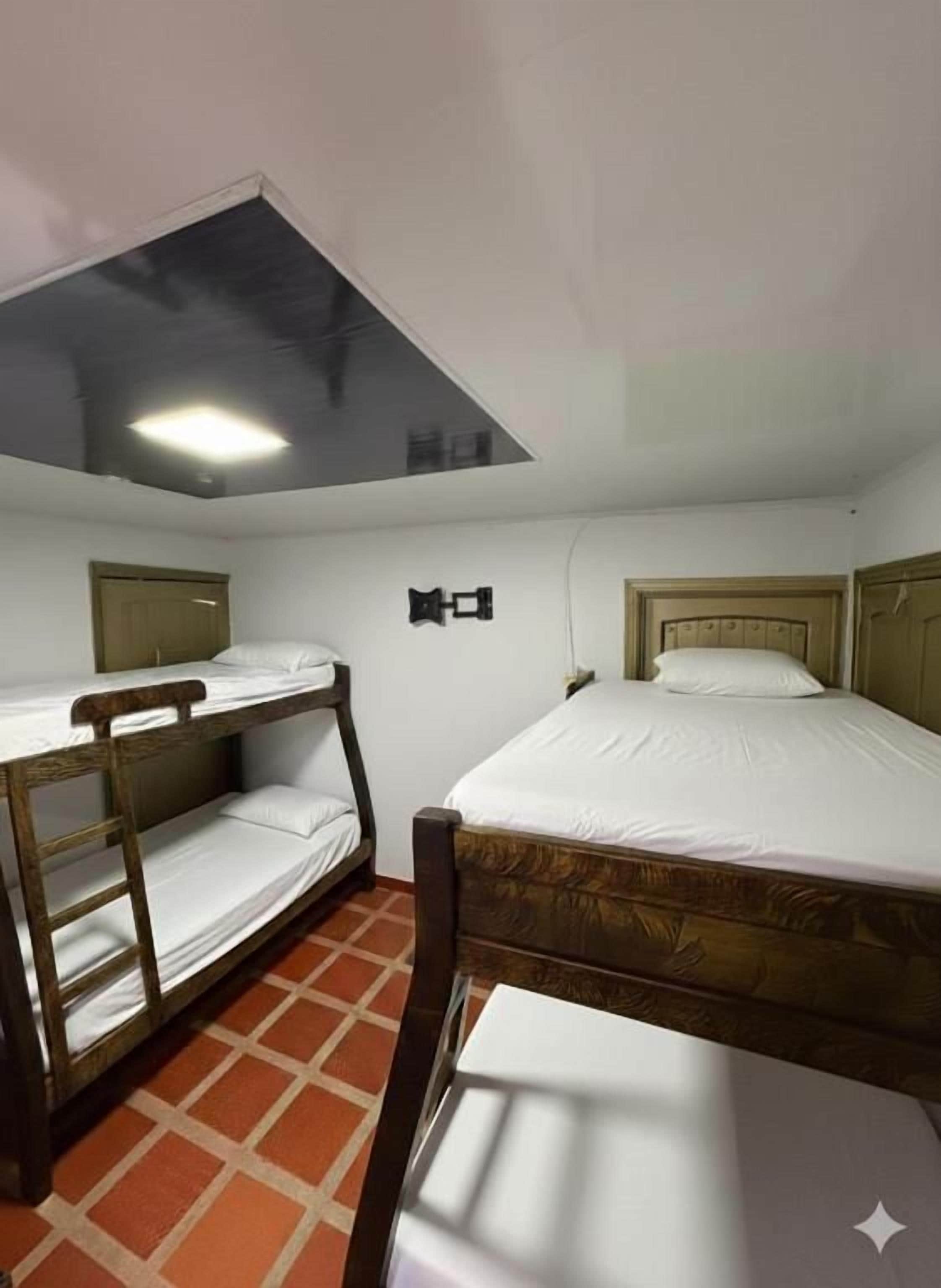 A room with bunk beds, a single bed, and a slanted ceiling.