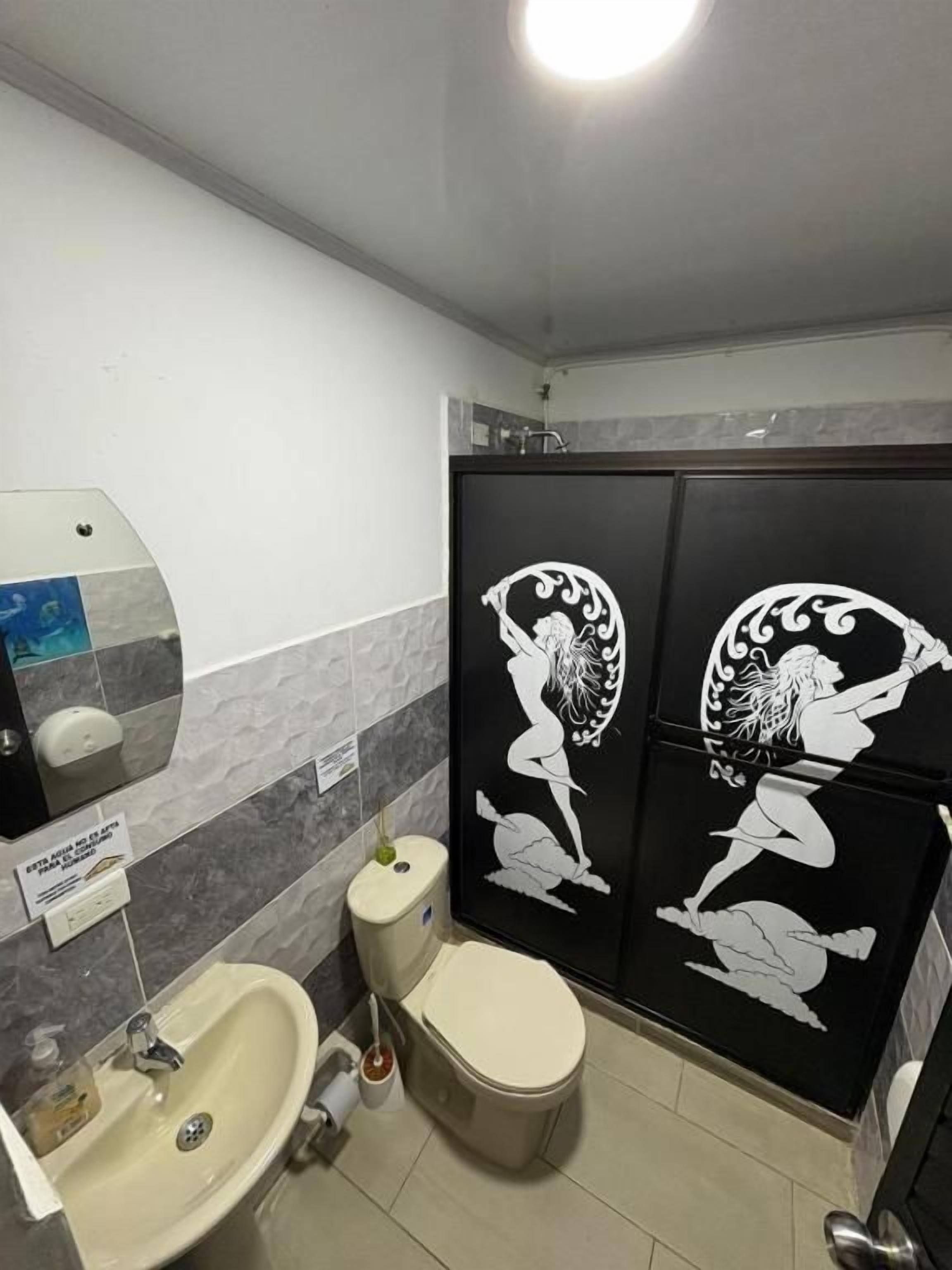 Un baño con inodoro, lavabo y decoración mural.