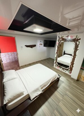 Quarto com cama, televisão na parede e uma decoração original.
