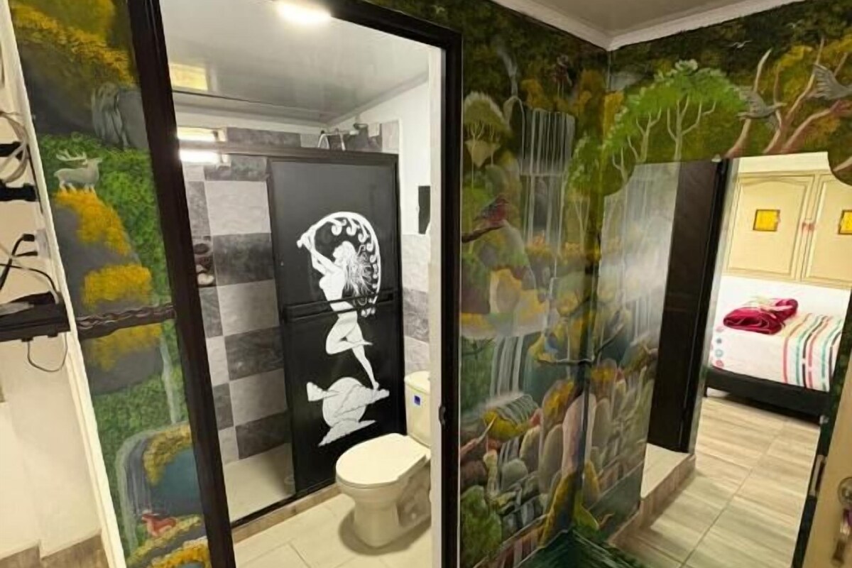 A bathroom with a mirror, toilet, and shower area.