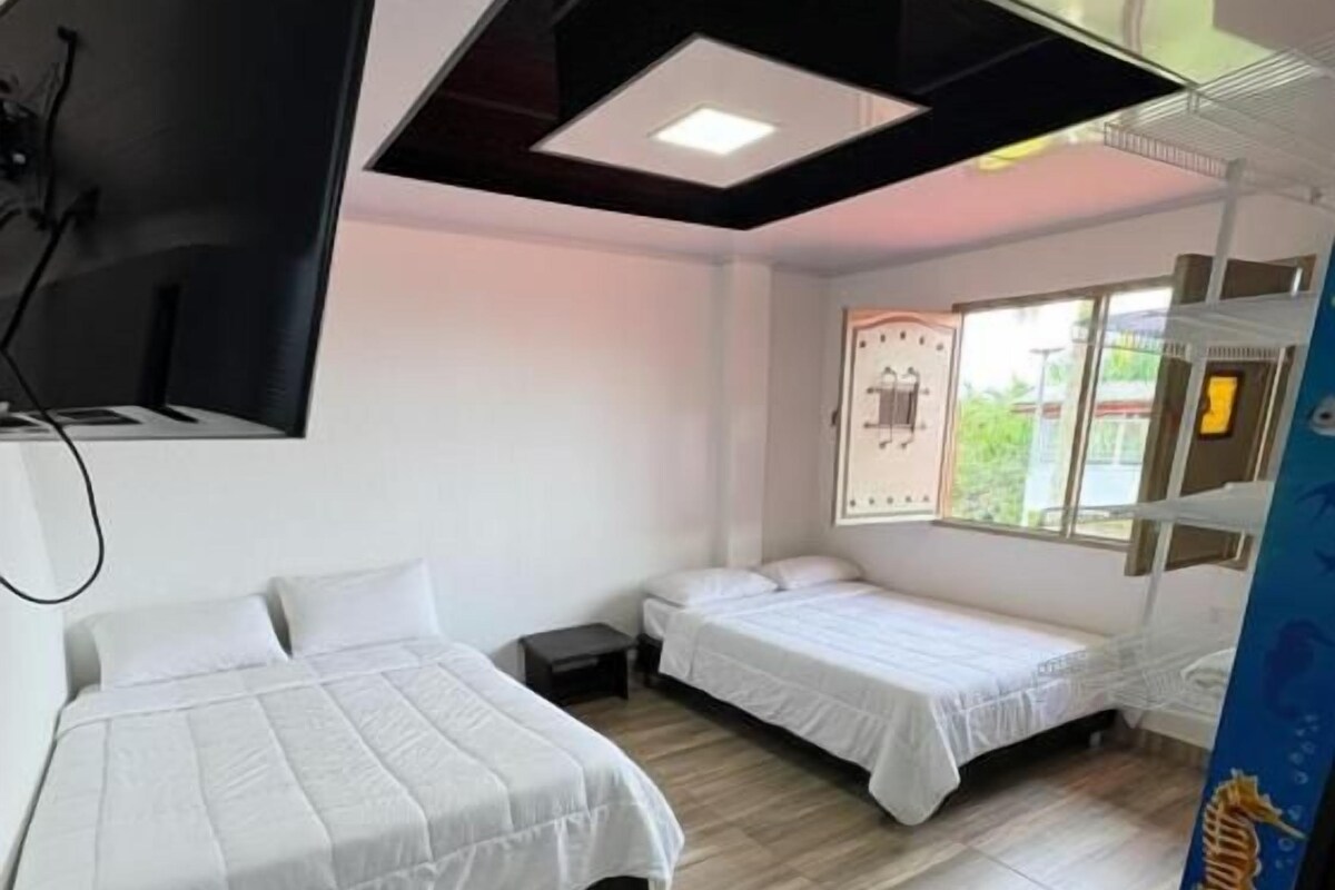 Quarto de hotel com duas camas, televisão de tela plana na parede e janela com vista para o exterior.