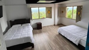 Une chambre avec deux lits, une petite table et une fenêtre donnant sur un paysage agréable.
