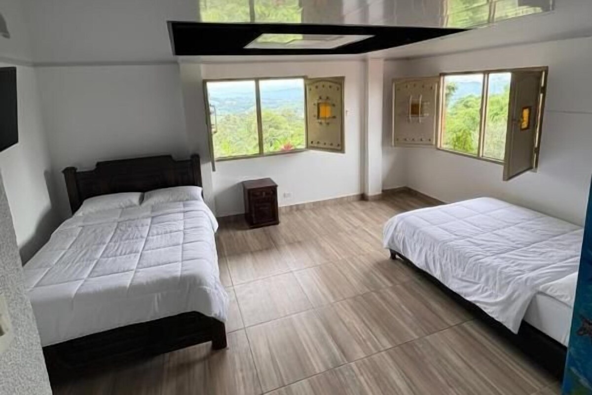 Quarto com duas camas, uma mesa pequena e janela com vista.