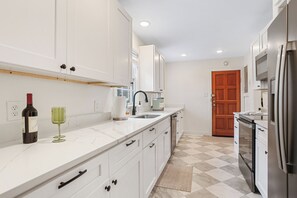 A modern kitchen with white cabinets, a stainless steel refrigerator, and a checkered floor. - 2bd/2ba Home * Renovated * 30+ Day Stay (Savannah)