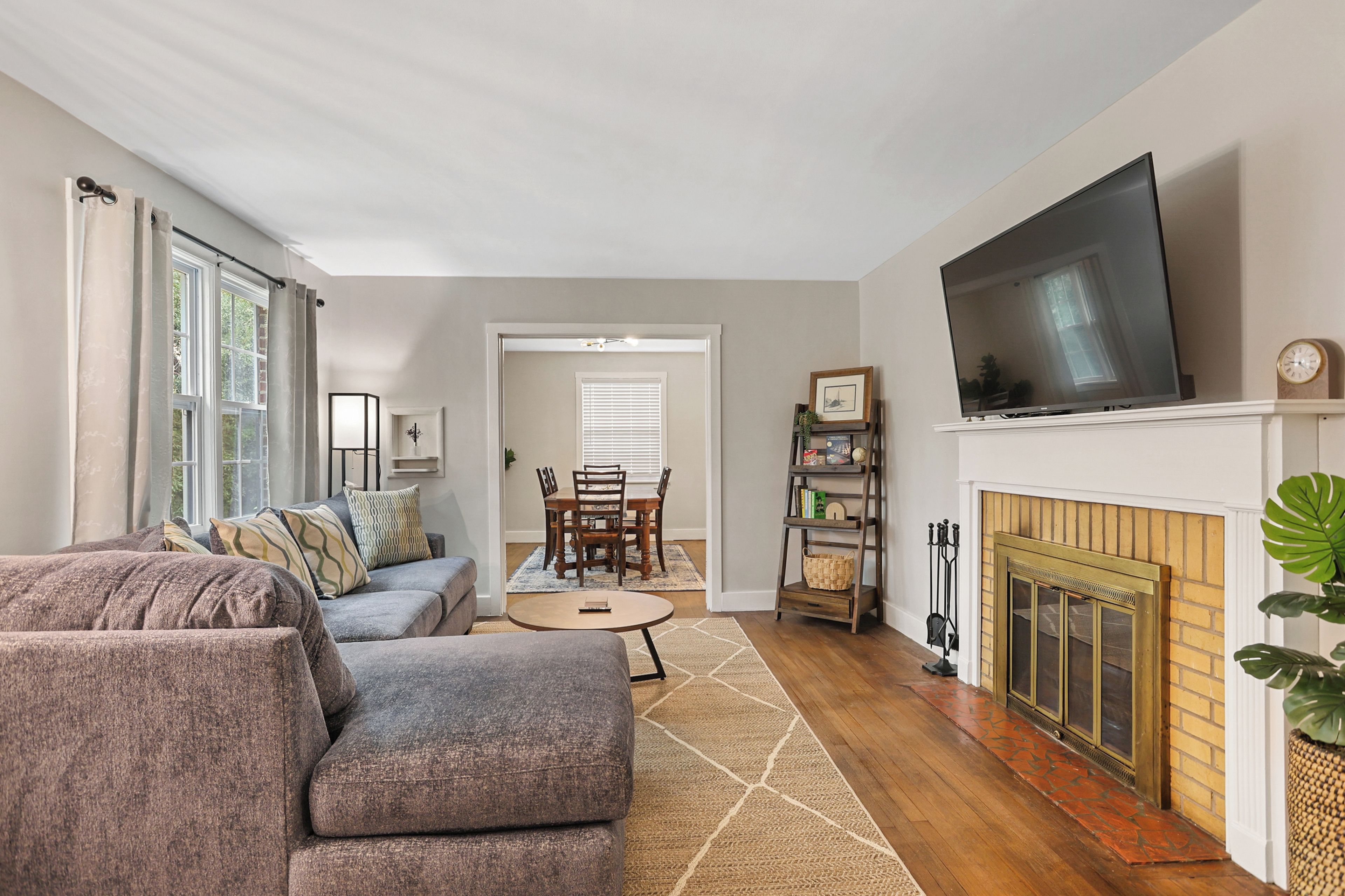 A living room with a sofa, television, fireplace, and dining area.