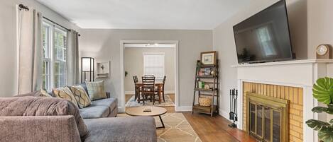 A living room with a sofa, television, fireplace, and dining area.