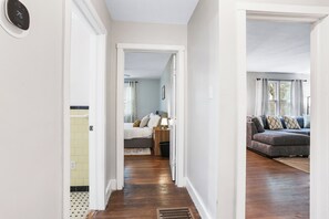 A hallway leading to a bedroom with a bed, bedside table, and a window. - 2bd/2ba Home * Renovated * 30+ Day Stay (Savannah)