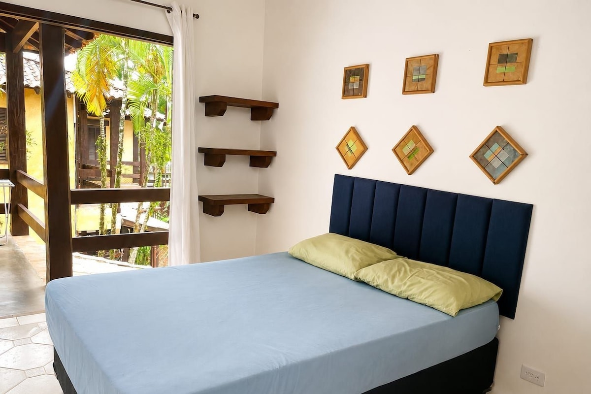 A bedroom with a bed, a window with curtains, and wall-mounted shelves.