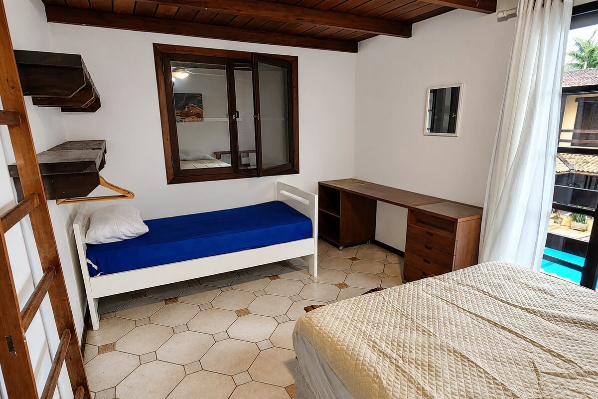 A bedroom with a bed, a desk, and a window.
