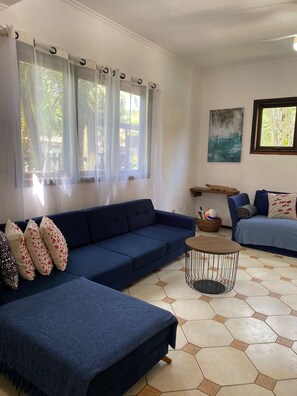 A living room with a blue sofa, a round coffee table, and a painting on the wall. - Villaggio Arcobaleno (São Sebastião)