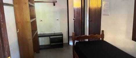 A bedroom with a wooden bed, a nightstand, a dresser, a wardrobe, and a door leading to another room.