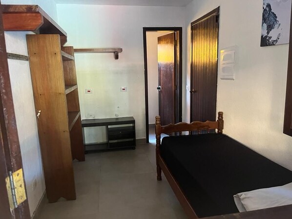 A bedroom with a wooden bed, a nightstand, a dresser, a wardrobe, and a door leading to another room. - Villaggio Arcobaleno (São Sebastião)