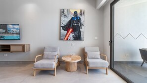 A modern living room with two grey armchairs, a round wooden coffee table, and a large Darth Vader artwork on the wall. - One 1702 Penthouse: Star Wars Oceanfront Penthouse| Sonoran Star Resort ⭐🌊 (Puerto Peñasco)