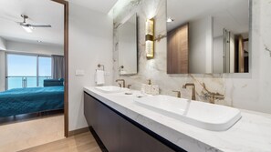 Une salle de bain moderne avec un grand miroir, deux lavabos et un ventilateur de plafond.