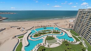 Un complexe hôtelier doté d’une grande piscine, situé en bord de mer et comprenant un immeuble de grande hauteur.