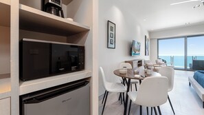 A modern kitchen with a built-in microwave and dishwasher, a dining area with white chairs, and a large window overlooking the sea. - One 1702 Penthouse: Star Wars Oceanfront Penthouse| Sonoran Star Resort ⭐🌊 (Puerto Peñasco)