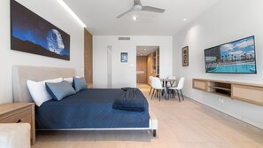 Une chambre d’hôtel moderne dotée d’un grand lit, d’un téléviseur à écran plat, d’un coin repas et d’un ventilateur de plafond.
