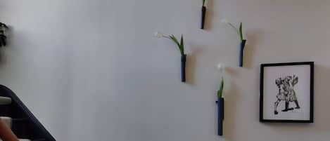 Un escalier avec des rampes en bois, un tableau accroché au mur et plusieurs plantes en pot.