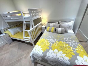 A bedroom with bunk beds, a bed with floral bedding, and a bedside table. - Modern Waterfront Oasis. Sunsets • Serenity • Dock (Brechin)