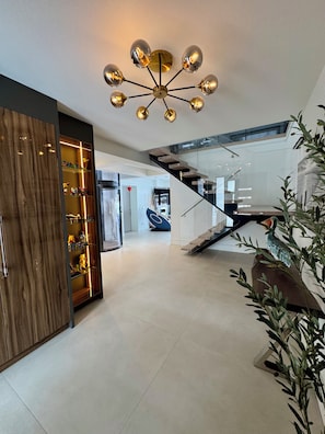 A modern interior with a staircase, a wooden cabinet with glass shelves, and a ceiling light fixture. - Modern Waterfront Oasis. Sunsets • Serenity • Dock (Brechin)