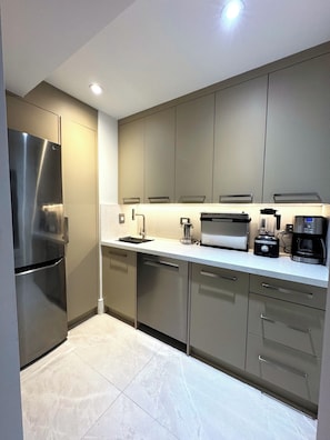 A modern kitchen with stainless steel appliances, a built-in oven, and a coffee maker. - Modern Waterfront Oasis. Sunsets • Serenity • Dock (Brechin)