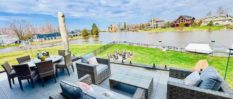 Un patio al aire libre con mobiliario de mimbre y vista a un lago.